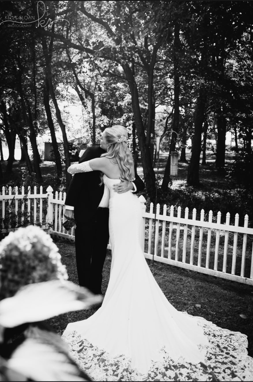 Bride and groom embrace by the picket fence